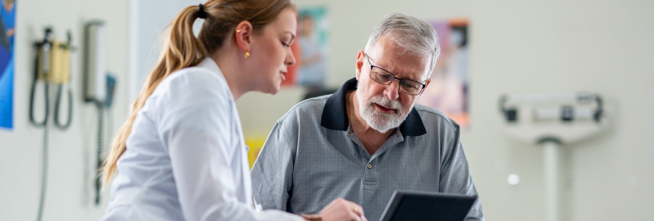 Eine Ärztin und ein Patient schauen zusammen auf ein Tablet