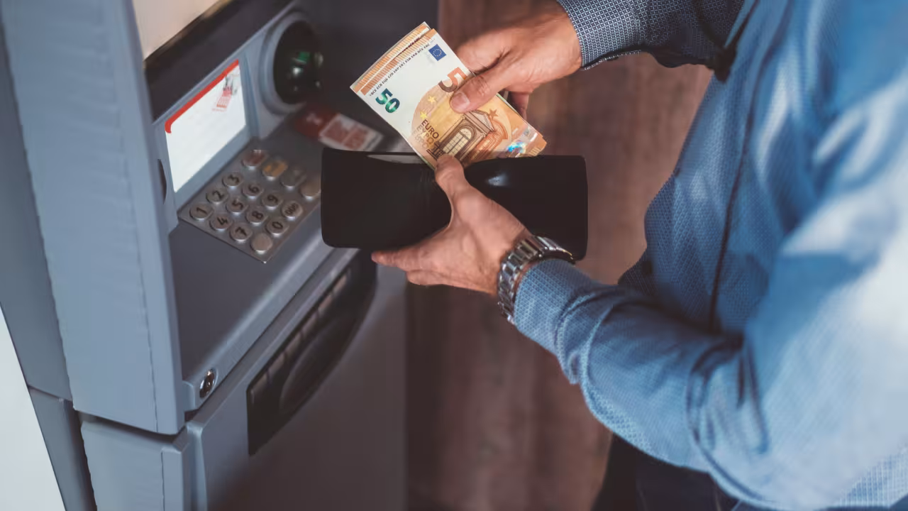 Person hebt Bargeld vom Automaten ab