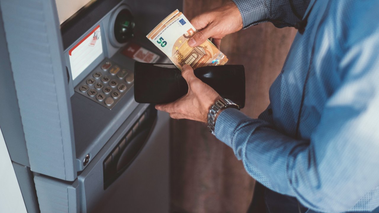Person hebt Bargeld vom Automaten ab