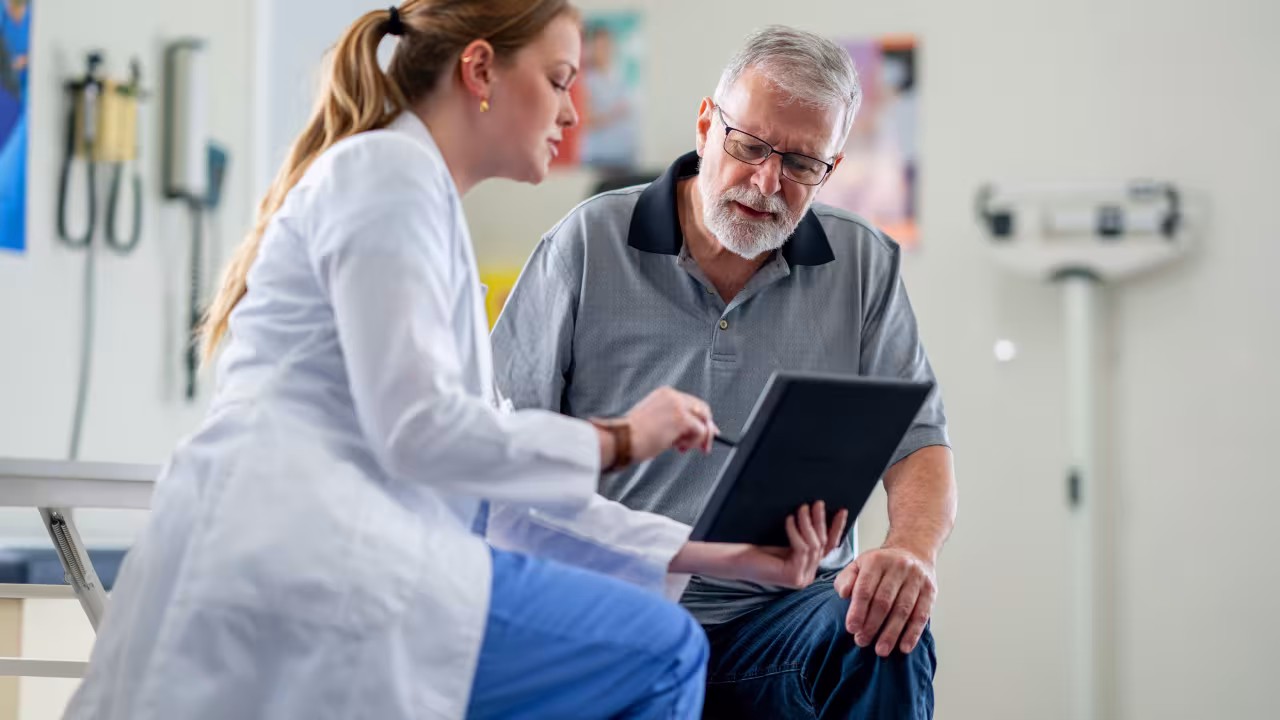 Eine Ärztin und ein Patient schauen zusammen auf ein Tablet