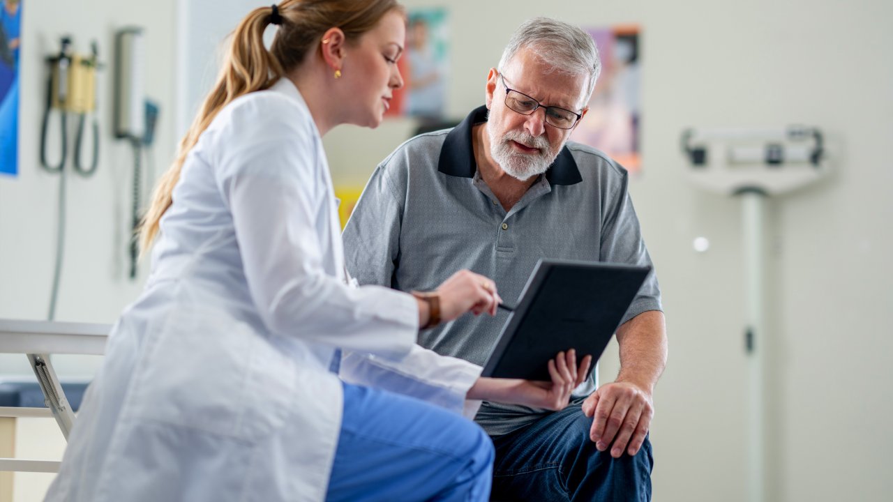 Eine Ärztin und ein Patient schauen zusammen auf ein Tablet