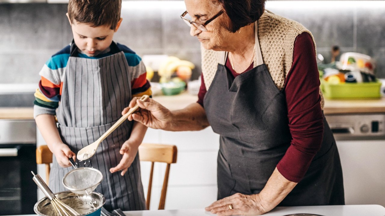 Ein Kind und eine ältere Frau stehen zusammen in der Küche und kochen