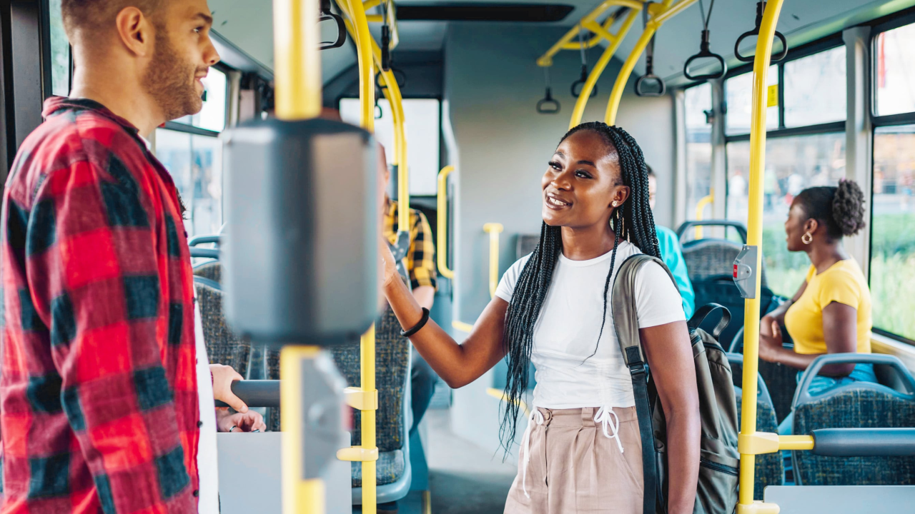 Ein Mann und eine Frau stehen im Bus voreinander und unterhalten sich.