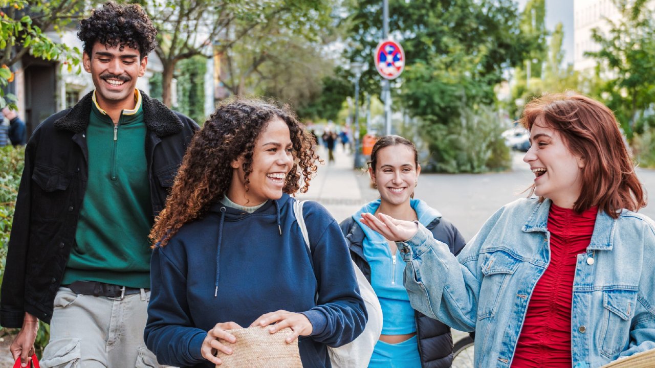 Eine Gruppe von Jugendlichen läuft fröhlich durch die Straße.